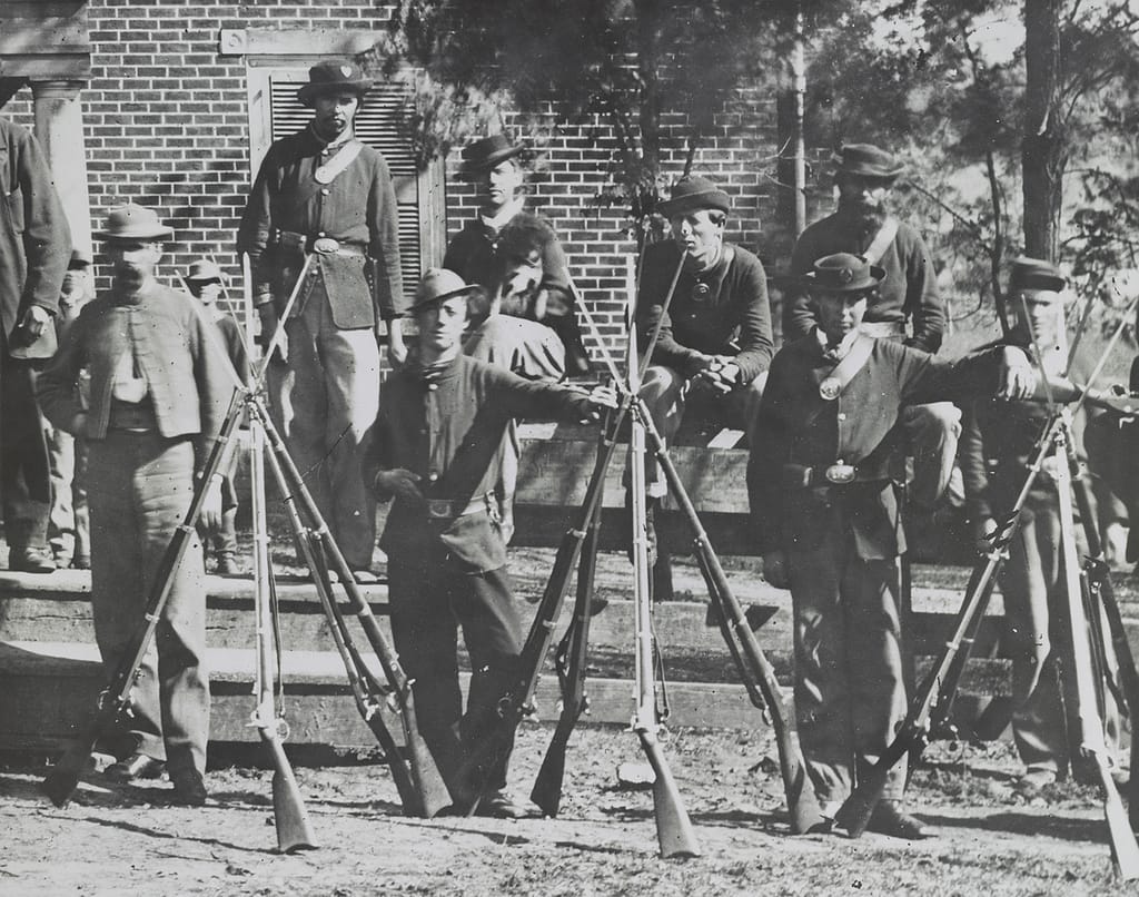 Photograph shows Union Veterans with Stacked Muskets at Appomattox Court House.